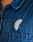 The pale color of the Feather pin is stark against a bright jean button down shirt.