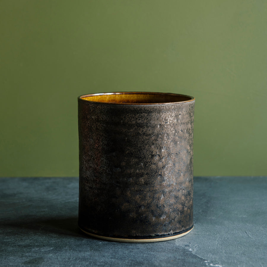 A close-up of the Graphite glaze shows its dappled surface - from shiny and smooth to more textured and metallic. The high variation found in this glaze is exemplified on the flat, vertical side of the Pewabic Crock.