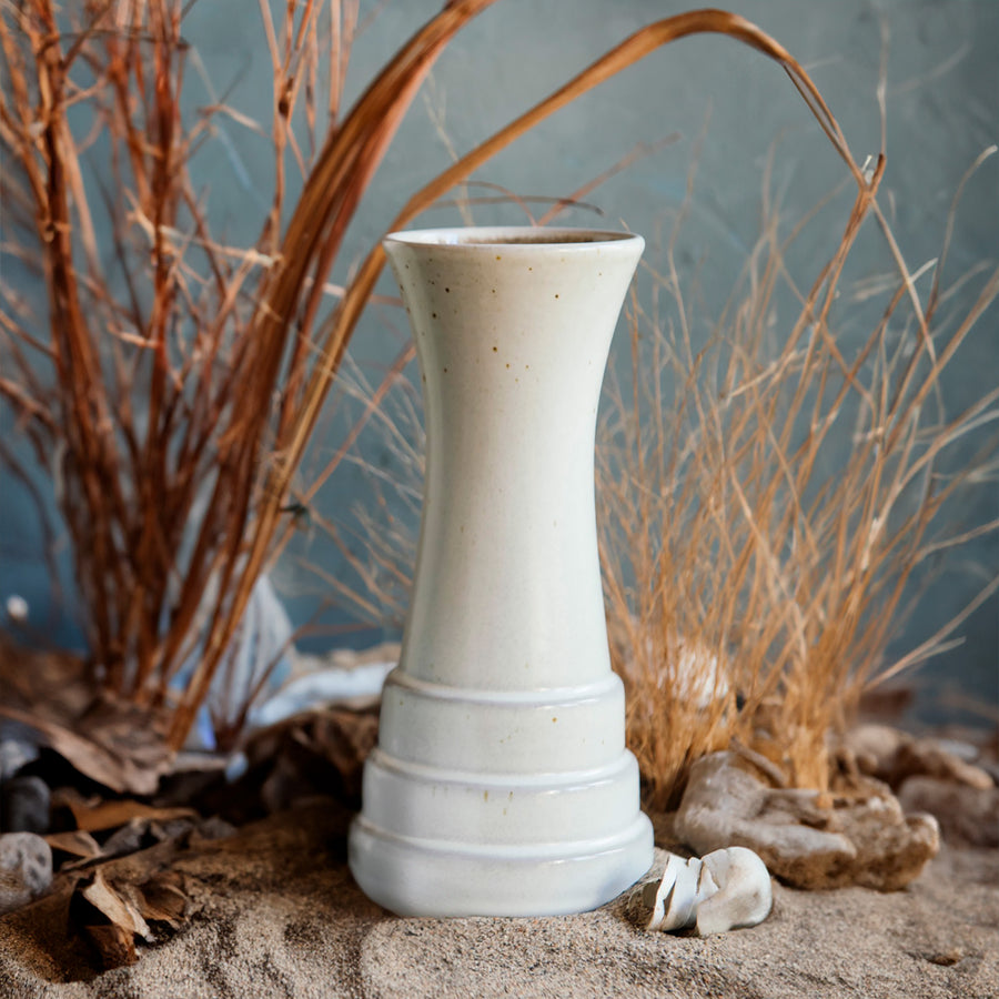 This Birch Step Vase sits in a diorama-like setting. Sand, rocks and brown grasses surround the vase, reminiscent of a Michigan day at the dunes. 