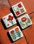 The Two Flowers Tile is on a bright red brick background with the other tiles in the Poppy color palette - the Rose Tile, the Cactus Flower Tile and the Four Flowers Tile.
