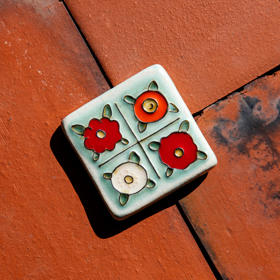 The Four Flowers Tile is segmented into four sections, each section has one flower inside it. The flowers have yellow centers and either red, deep orange or white petals.
