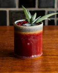 One Pewabic Rocks Cups in our glossy-red Winterberry glaze on a wood foreground with cranberries and sage.