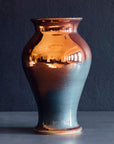 The Large Classic Vase starts with a small diameter at its base that gradually gets larger until it contracts again near the top with a slightly wider lip. The surface of the vase is smooth.