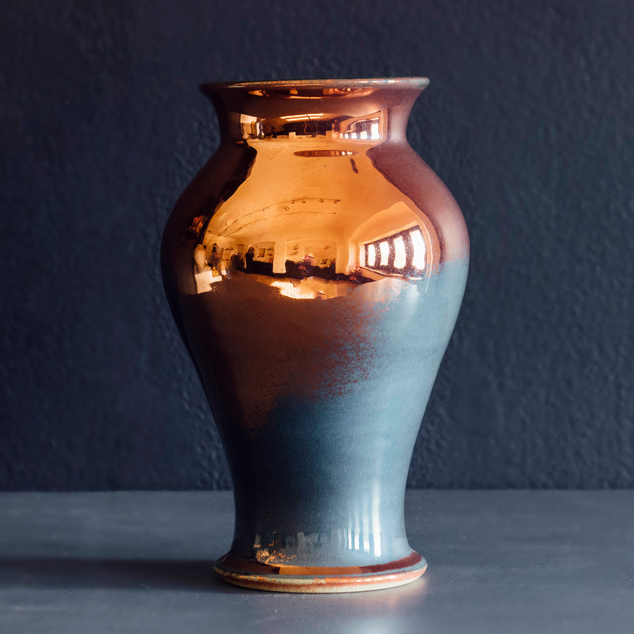 The Large Classic Vase starts with a small diameter at its base that gradually gets larger until it contracts again near the top with a slightly wider lip. The surface of the vase is smooth.