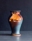 The Medium Classic Vase starts with a small diameter at its base that gradually gets larger until it contracts again near the top with a slightly wider lip. The sides of the vase are completely smooth.