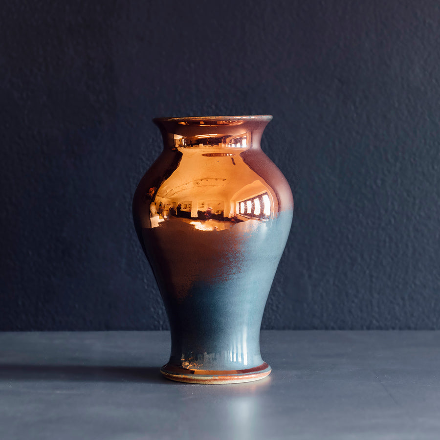 The Medium Classic Vase starts with a small diameter at its base that gradually gets larger until it contracts again near the top with a slightly wider lip. The sides of the vase are completely smooth.