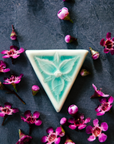 This inverted triangle shaped pin features a delicately sculpted three petaled trillium flower. The pin comes in our glossy pale blue Celadon glaze.