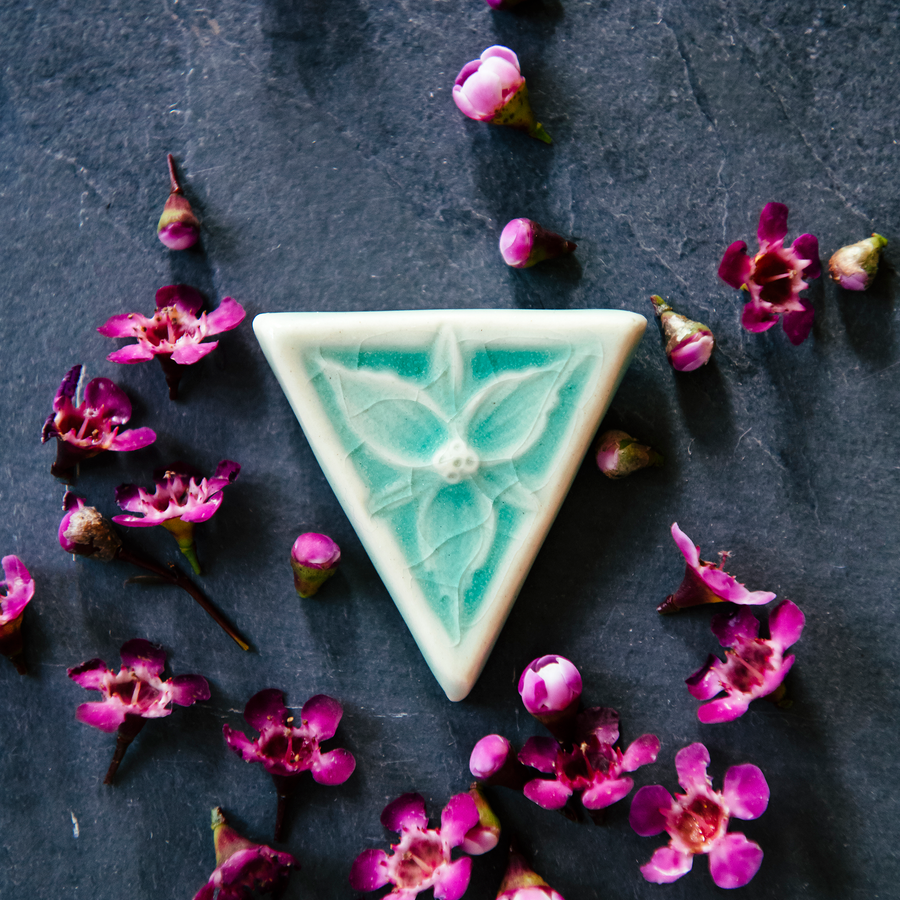 This inverted triangle shaped pin features a delicately sculpted three petaled trillium flower. The pin comes in our glossy pale blue Celadon glaze.