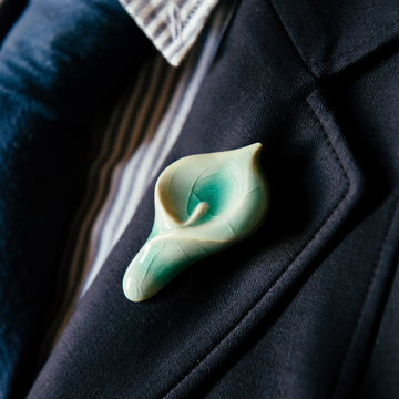 Ceramic Calla Lily Pin in pale glossy blue glaze used as a boutonniere on a suit lapel.