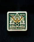 The Wayne State University tile is displayed on a map of Detroit. The tile boasts a prominent W in the center of the design that is hovering over a simple line drawing of the Old Main. On the bottom of the tile "Wayne State" is written in bold lettering and the dates 1868 and 2018 are displayed across the top- in celebration of Wayne State's 150 years as a learning institution. This whole design is depressed into a flat tile. The depressions hold glossy green and gold glaze.